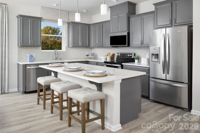 a kitchen with stainless steel appliances granite countertop a stove a refrigerator a microwave a sink and chairs