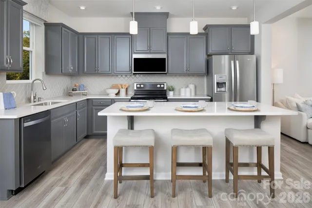 a kitchen with stainless steel appliances granite countertop a dining table chairs refrigerator sink and cabinets