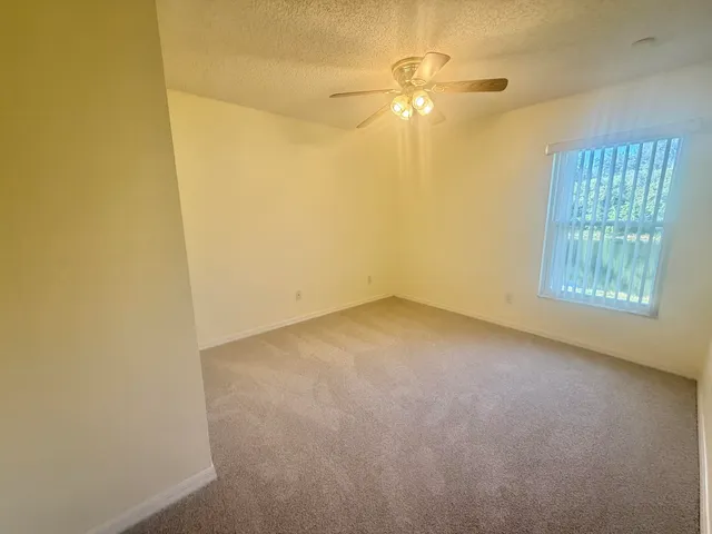 an empty room with windows and fan