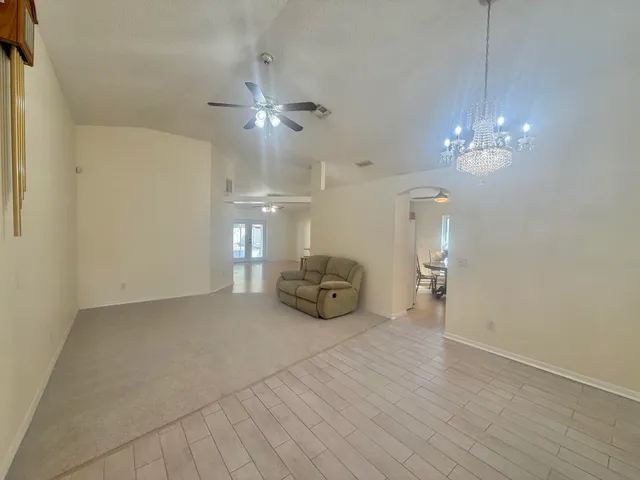 a view of an empty room with a chandelier fan