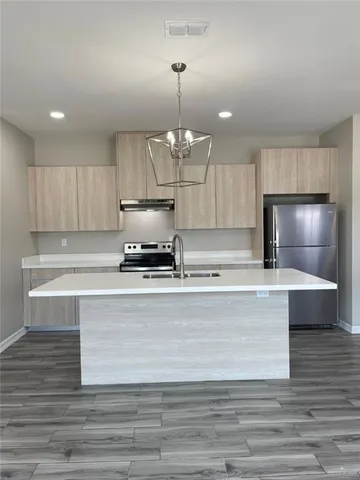 a kitchen with kitchen island granite countertop a stove and a wooden floors