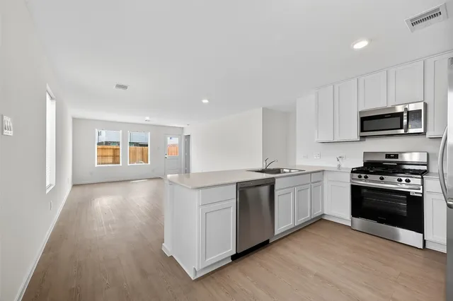 a kitchen with stainless steel appliances granite countertop a stove a sink and a microwave