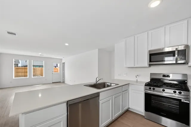 a kitchen with stainless steel appliances a sink dishwasher stove and microwave with wooden floor