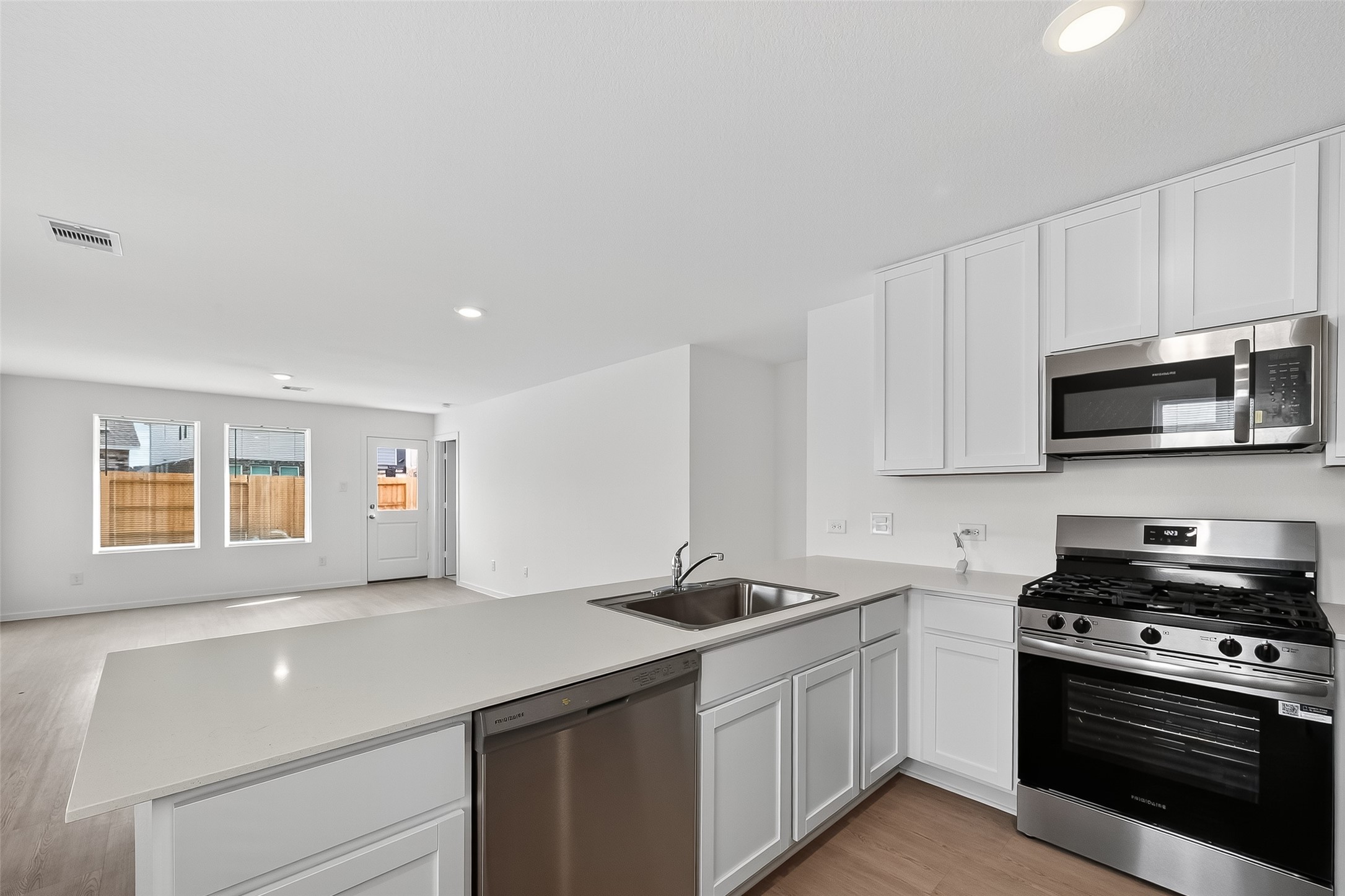 18510 Autumn Hts Lane Crosby, TX 77532 - Photo 10 of 29 a kitchen with stainless steel appliances a sink dishwasher stove and microwave with wooden floor