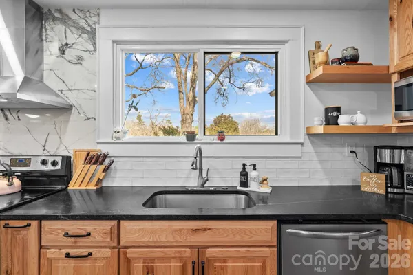 a kitchen with stainless steel appliances granite countertop a sink dishwasher stove and white cabinets with wooden floor
