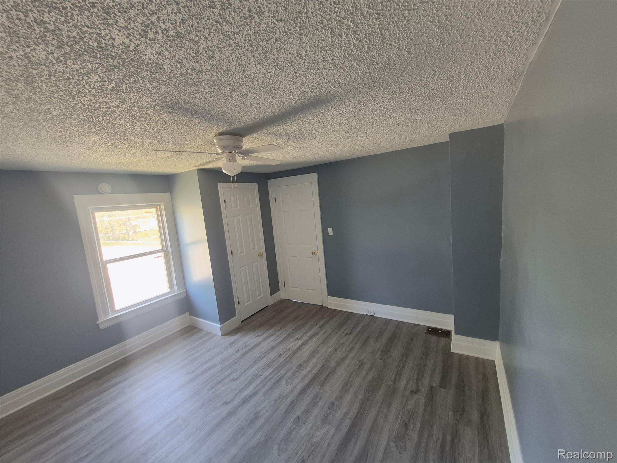 16758 Frazho Road Roseville, MI 48066 - Photo 42 of 53 Room featuring light gray wood-finish flooring, white baseboards, a single window with white trim, two white paneled doors, and a ceiling fan