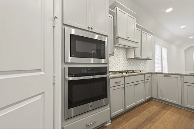 a kitchen with stainless steel appliances white cabinets and a stove top oven