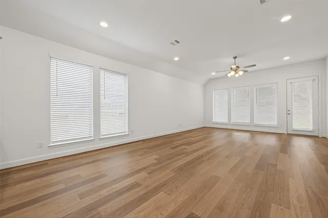 a view of an empty room with wooden floor and window