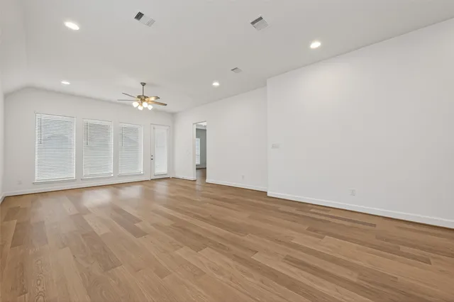 an empty room with wooden floor and natural light