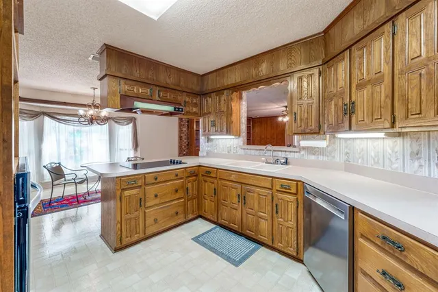 a kitchen with granite countertop a sink cabinets stainless steel appliances and a large window