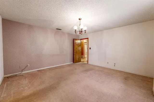 an empty room with chandelier fan and windows