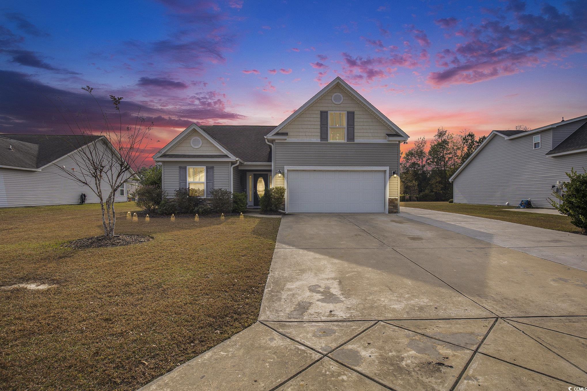 Traditional-style home featuring driveway, an attached garage, a yard, and stone siding
