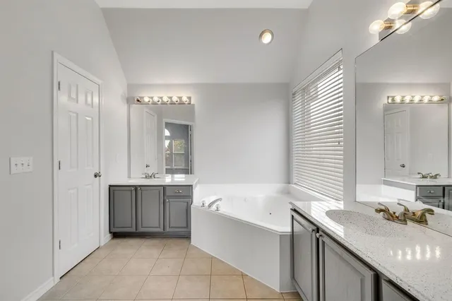 a bathroom with a double vanity sink mirror and bathtub