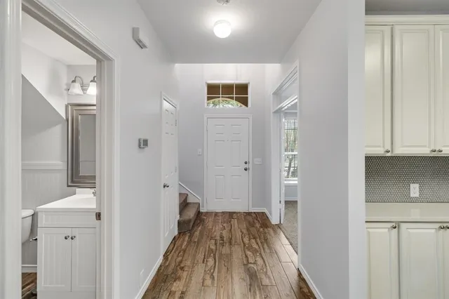 a view of a hallway with wooden floor and a bathroom