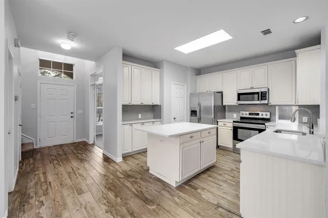 a kitchen with a sink cabinets stainless steel appliances and a window