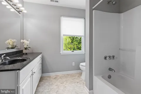 a bathroom with a granite countertop sink a toilet a bathtub and shower