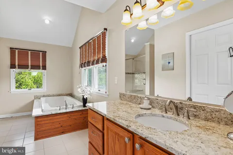 a bathroom with a granite countertop sink a large mirror and a bathtub
