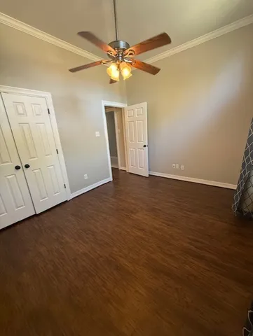 an empty room with wooden floor fan and window
