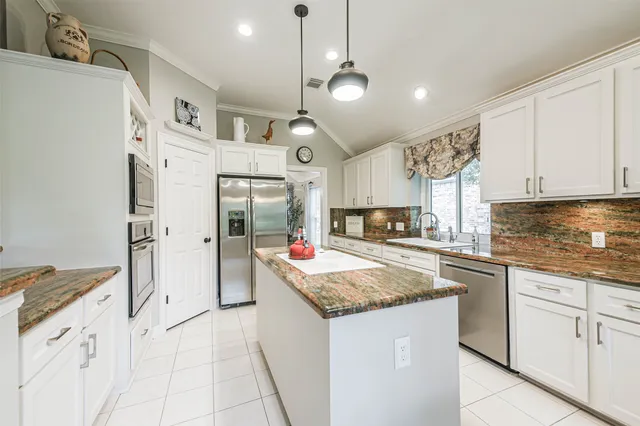 a kitchen with stainless steel appliances granite countertop a sink and a refrigerator