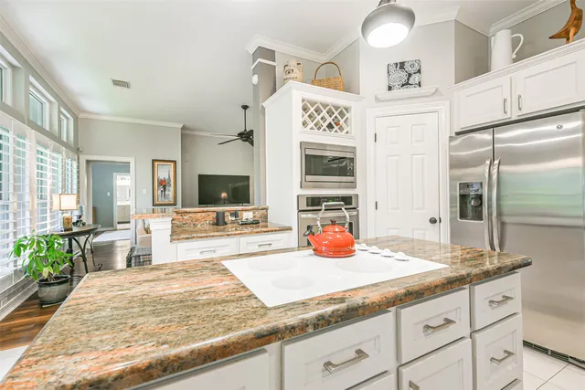 a view of a kitchen with kitchen island a sink appliances and cabinets