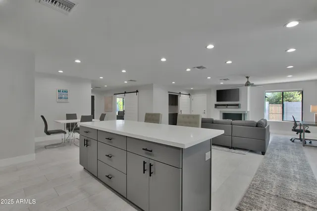 a view of kitchen with kitchen island a sink wooden floor dining table and chairs
