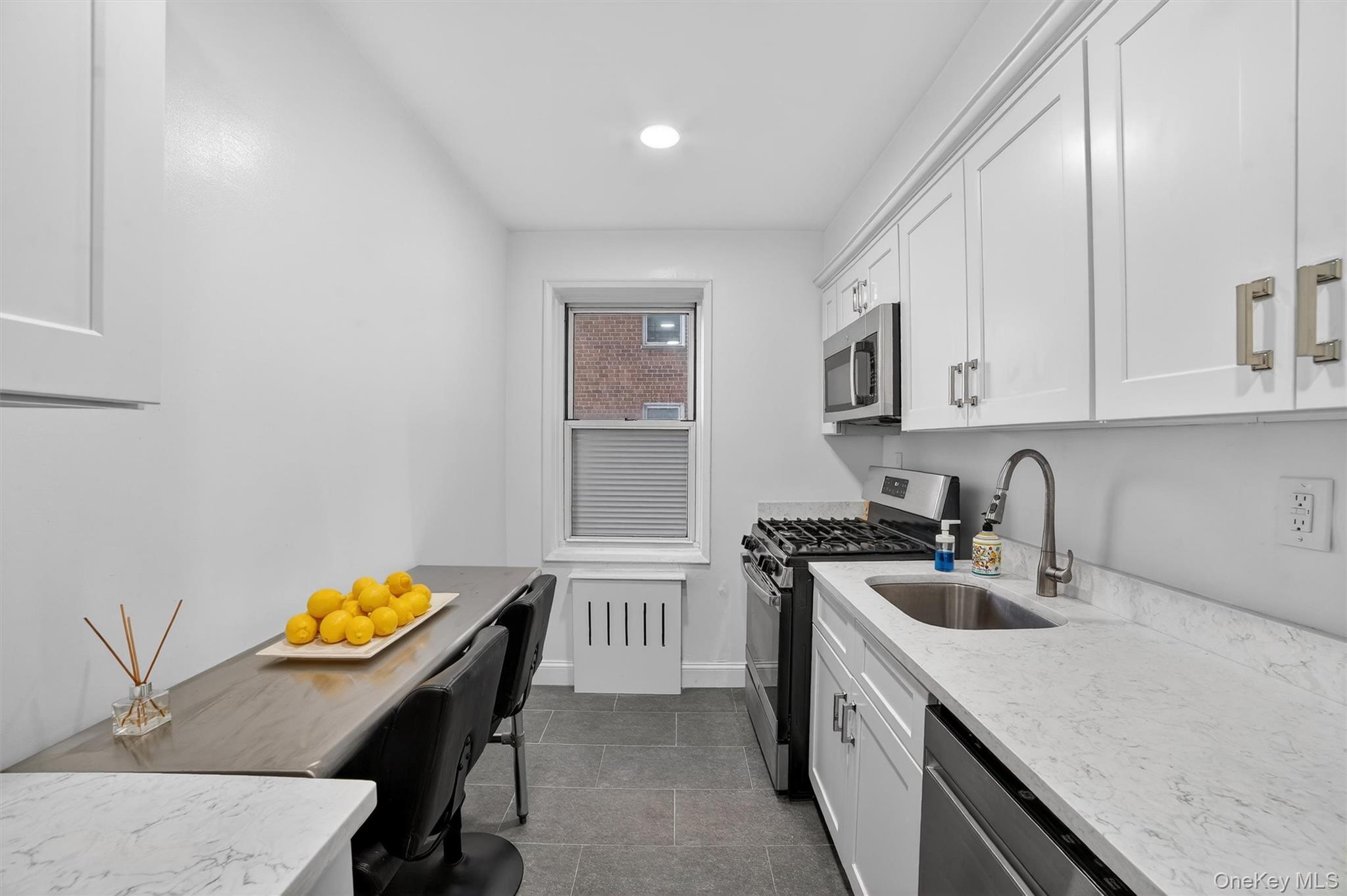 60 Locust Avenue, Unit 214A New Rochelle, NY 10801 - Photo 13 of 20 Kitchen with appliances with stainless steel finishes, light stone countertops, white cabinetry, recessed lighting, and dark tile patterned floors