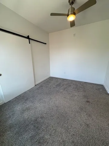 an empty room with a fan & a window