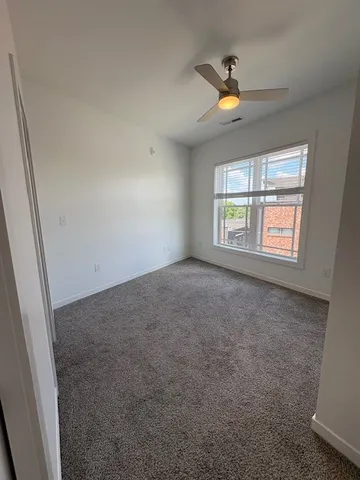 an empty room with windows and ceiling fan