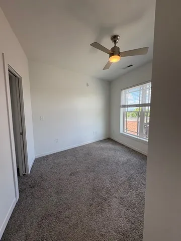 an empty room with windows and fan