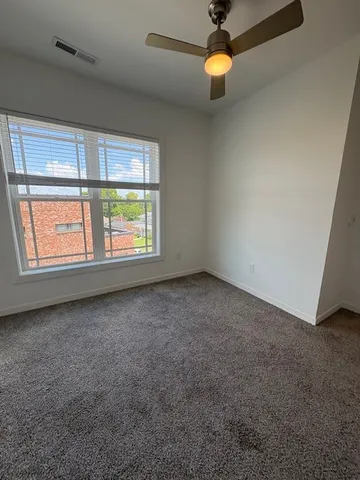 an empty room with windows and fan