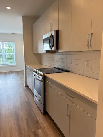 a kitchen with stainless steel appliances white cabinets and wooden floor