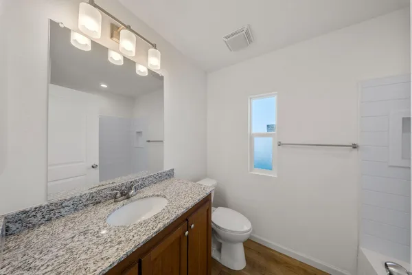 a bathroom with a granite countertop sink a toilet and a mirror