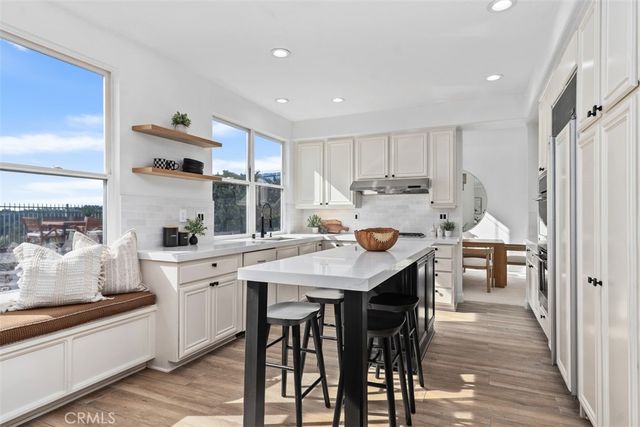 a kitchen with stainless steel appliances granite countertop a sink a stove and white cabinets