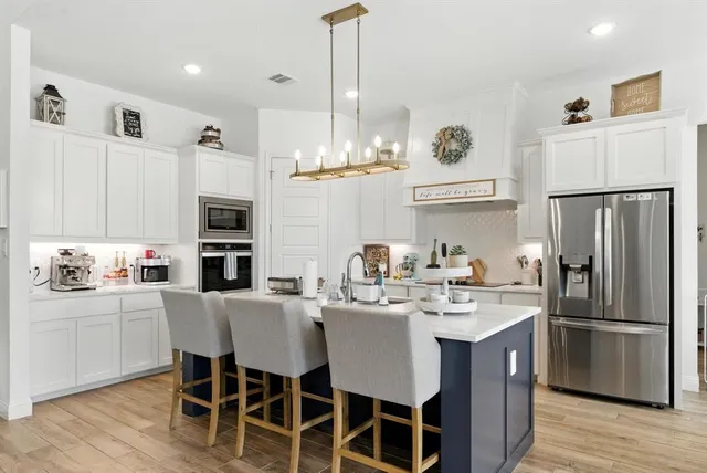 a kitchen with stainless steel appliances a table chairs refrigerator and cabinets