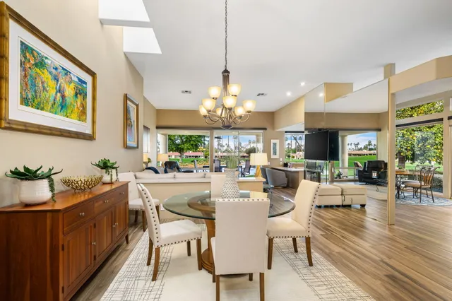 a view of a dining room and livingroom with furniture wooden floor a rug a painting and a chandelier
