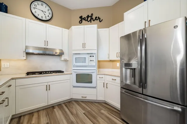 a kitchen with stainless steel appliances a refrigerator a stove and white cabinets