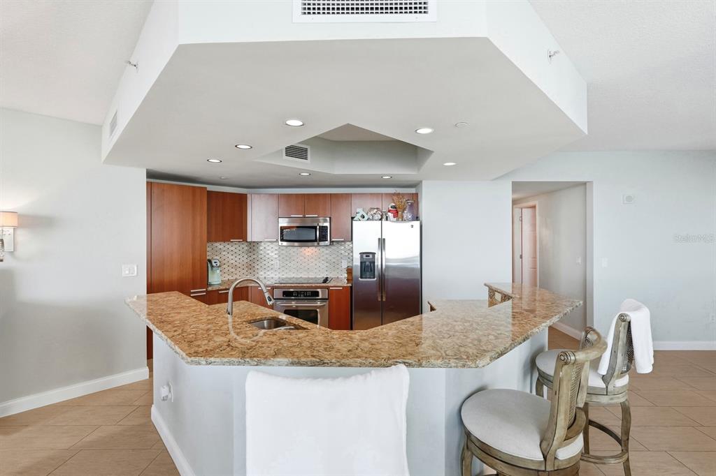 231 Riverside Drive, Unit 1702 Holly Hill, FL 32117 - Photo 18 of 74 a kitchen with granite countertop kitchen island stainless steel appliances a sink and a refrigerator