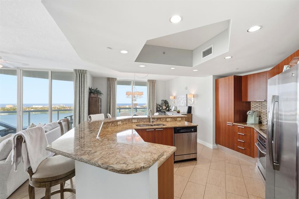 231 Riverside Drive, Unit 1702 Holly Hill, FL 32117 - Photo 21 of 74 a kitchen with stainless steel appliances granite countertop a refrigerator a sink dishwasher a stove and a dining table with wooden floor