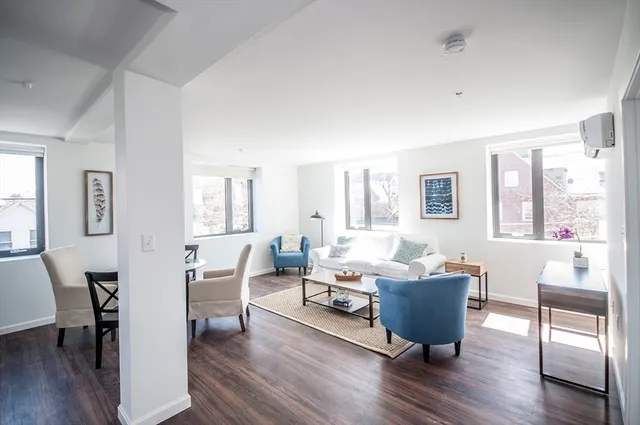 a living room with furniture a wooden floor and a large window