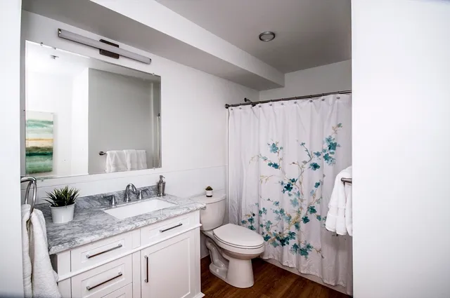 a bathroom with a granite countertop sink toilet and shower