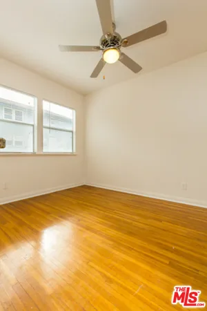 an empty room with a chandelier fan and windows