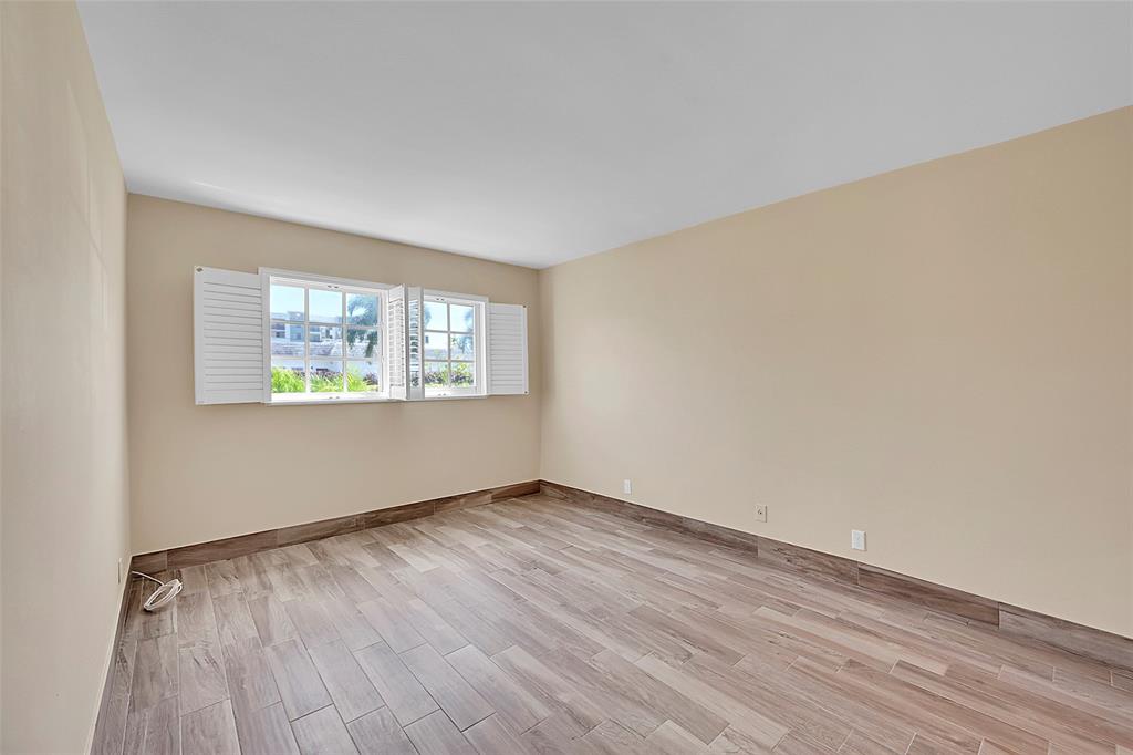3002 Northeast 5th Terrace, Unit 102B Wilton Manors, FL 33334 - Photo 19 of 44 an empty room with wooden floor and windows