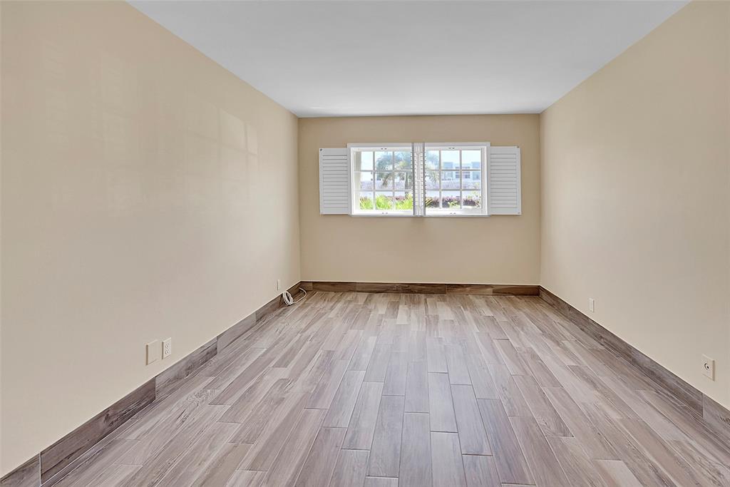 3002 Northeast 5th Terrace, Unit 102B Wilton Manors, FL 33334 - Photo 20 of 44 an empty room with wooden floor and windows
