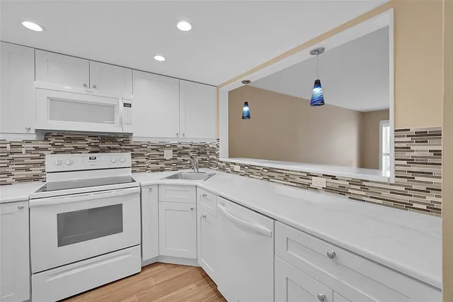a kitchen with white cabinets and appliances