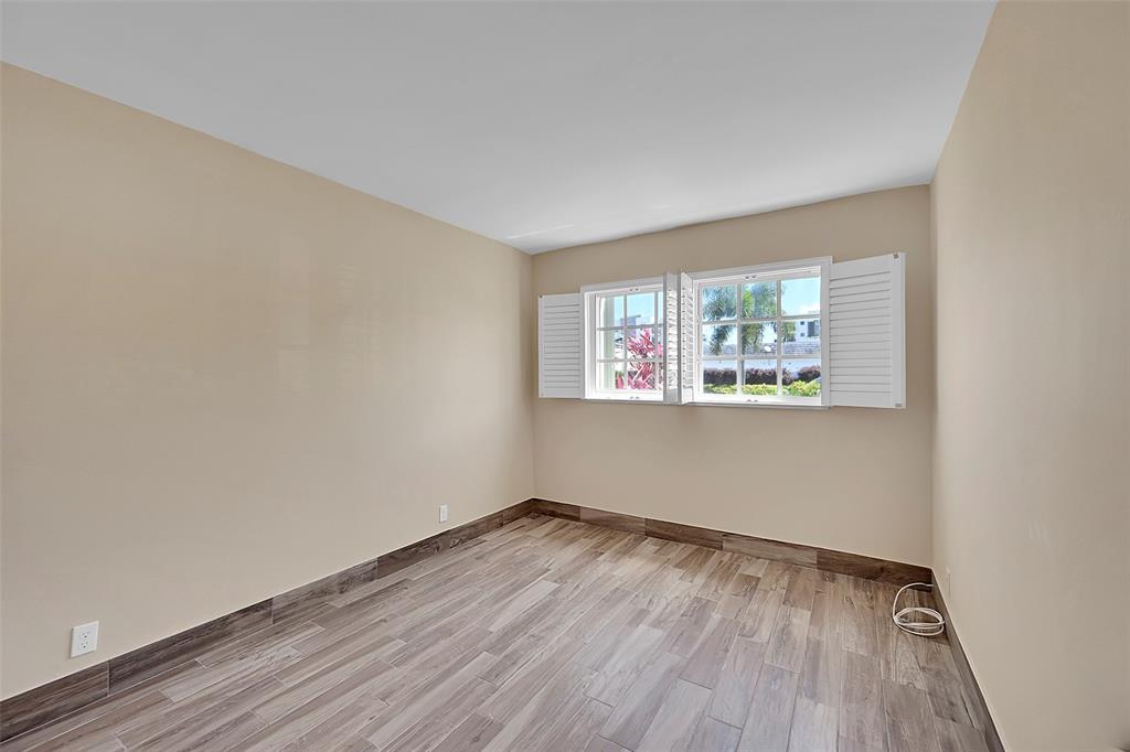 3002 Northeast 5th Terrace, Unit 102B Wilton Manors, FL 33334 - Photo 24 of 44 an empty room with wooden floor and windows