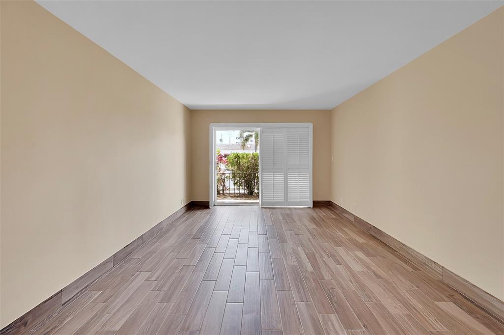 3002 Northeast 5th Terrace, Unit 102B Wilton Manors, FL 33334 - Photo 8 of 44 an empty room with wooden floor and windows