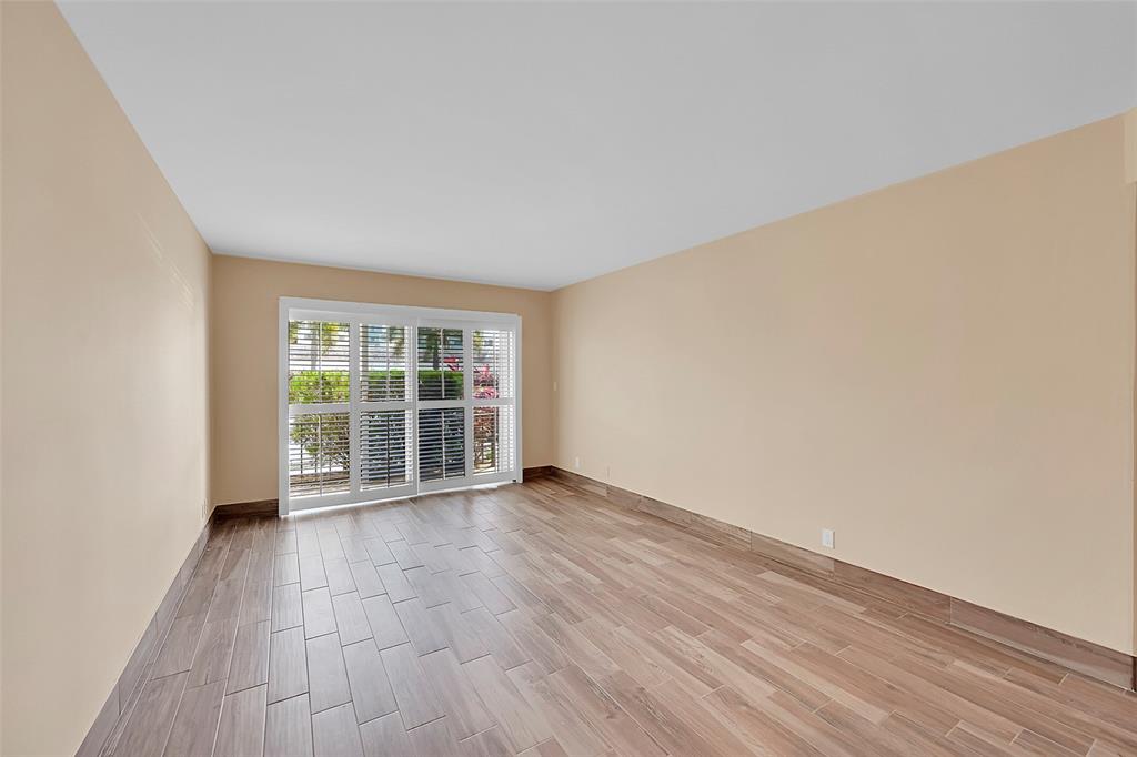 3002 Northeast 5th Terrace, Unit 102B Wilton Manors, FL 33334 - Photo 10 of 44 an empty room with wooden floor and windows