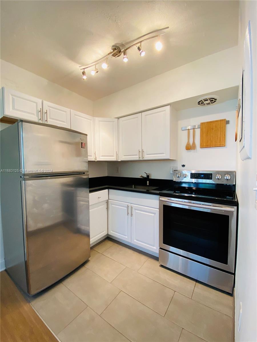 541 Northeast 63rd Street, Unit 3 Miami, FL 33138 - Photo 7 of 19 a kitchen with granite countertop a refrigerator and a stove
