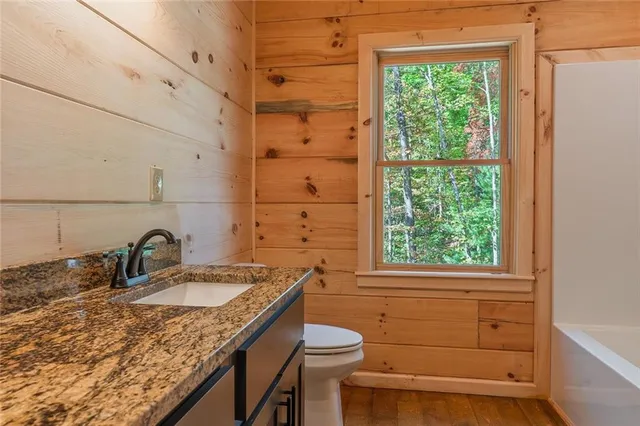a bathroom with a granite countertop sink toilet and mirror