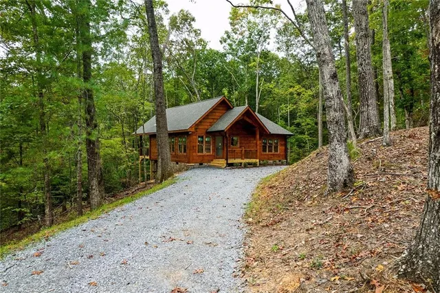 a front view of a house with a yard and large trees